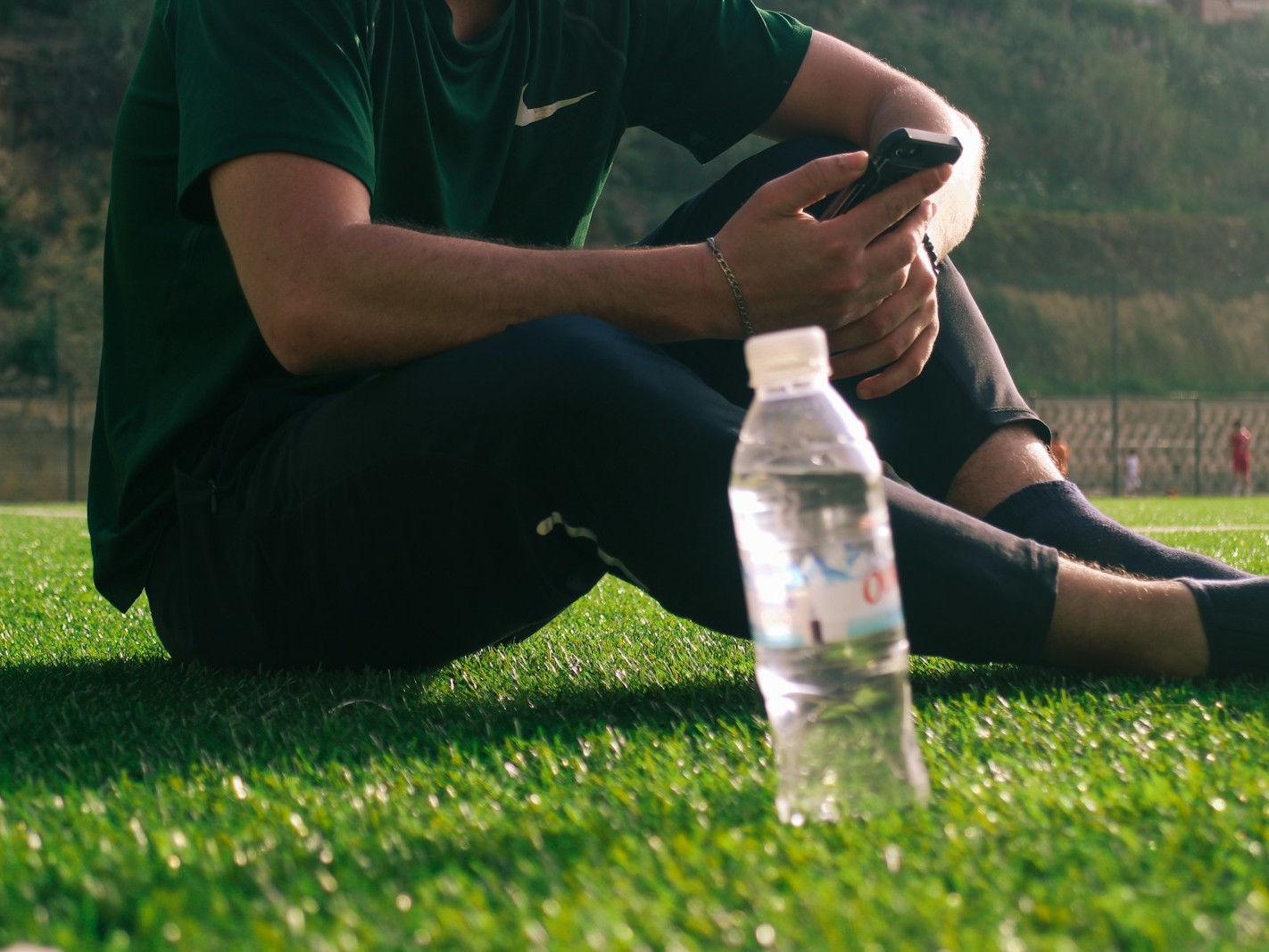 a man sitting on the grass with a bottle of water
